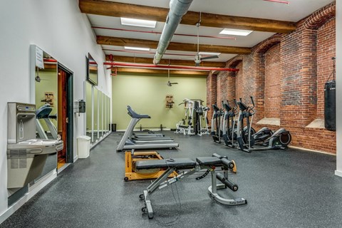 A gym with a variety of equipment including treadmills, weights, and exercise machines.