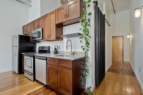 A kitchen with wooden cabinets and a black refrigerator.