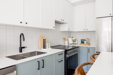 A kitchen with white and blue cabinets and a white countertop.
