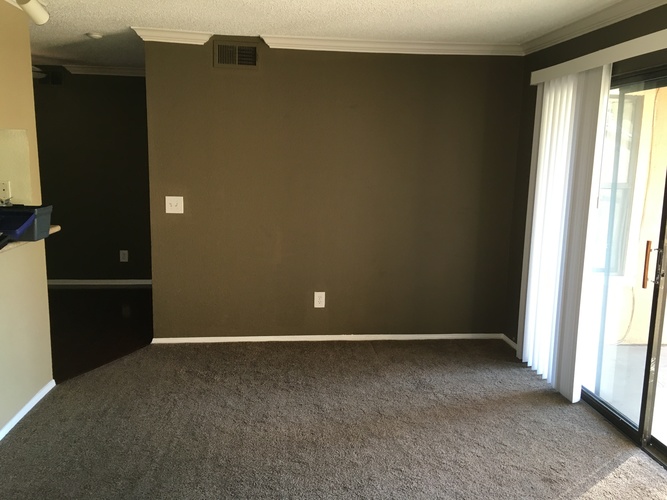 A room with a carpeted floor and a sliding glass door.
