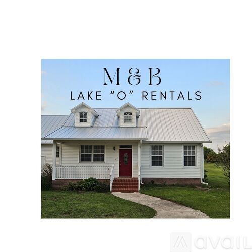 A white house with a red door and a sign that says M&B Lake "O" Rentals.
