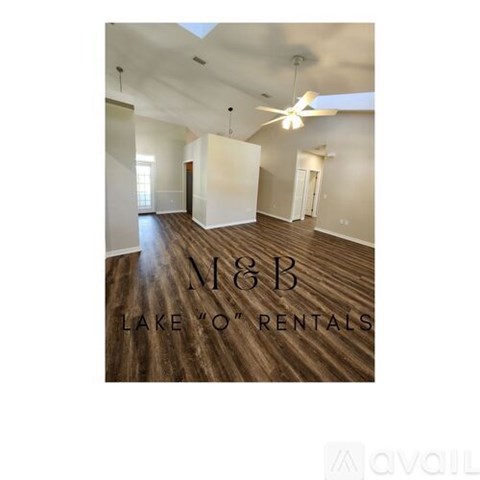 A spacious room with wooden flooring and a ceiling fan, with the text "M&B Lake 'O' Rentals" on the floor.