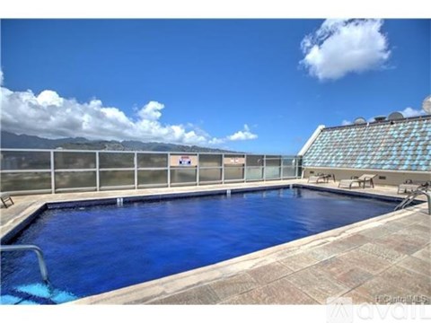 A large outdoor swimming pool with a glass wall and a tiled floor.
