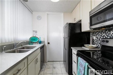 A kitchen with a black refrigerator, black oven, and black microwave.