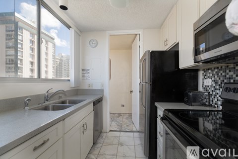 A kitchen with black appliances and a white clock on the wall.