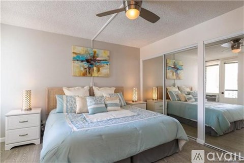 A bedroom with two beds, a ceiling fan, and a painting on the wall.