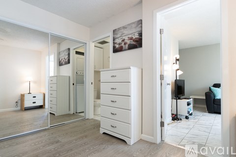 A bedroom with a white dresser and mirror.