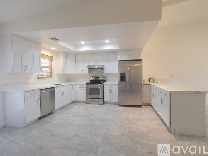 A modern kitchen with white cabinets and stainless steel appliances.
