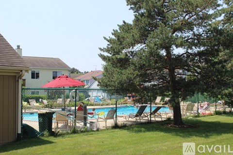 A pool area with a red umbrella and a tree in the foreground.