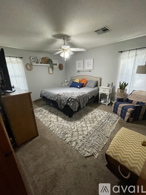 A bedroom with a bed, dresser, and ceiling fan.