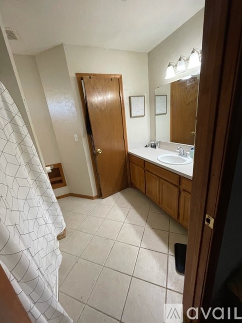 A bathroom with a white tiled floor and a wooden door.