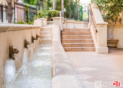 A small waterfall flows into a pool in a courtyard.