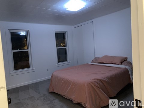 A bedroom with a bed and two windows.
