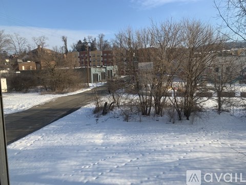 A snowy landscape with a road and buildings in the background.