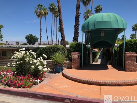 A green water tank is in the middle of a garden with a pathway leading to it.
