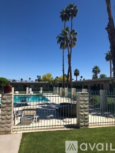 A pool surrounded by a fence with palm trees in the background.