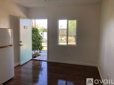 A room with a white door and a window with a view of a building and trees outside.