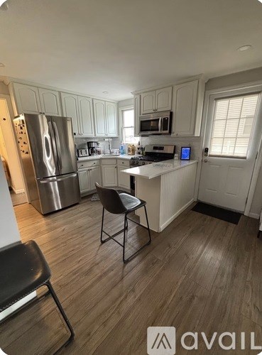 A kitchen with a refrigerator, a microwave, a stove, and a dining table with two chairs.