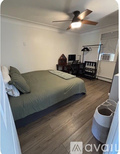 A bedroom with a bed, a chair, and a ceiling fan.