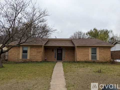 A house with a brown roof and a tree in front of it.