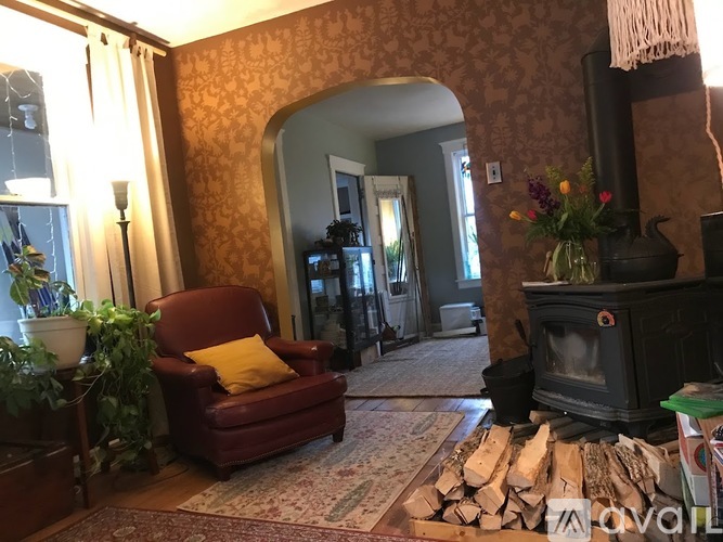A living room with a red chair and a fireplace.