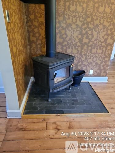 A wood stove is in a room with a yellow wallpaper.
