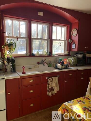 A kitchen with red cabinets and a white dishwasher.