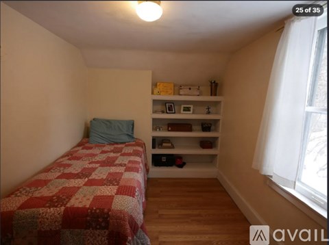 A bedroom with a bed, a window, and a shelf with various items.