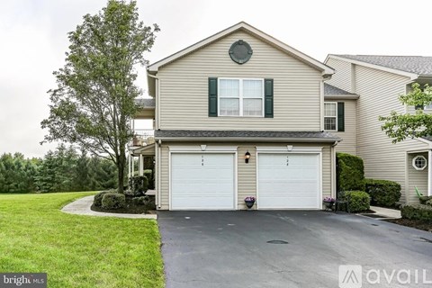 A two-car garage is attached to a house with a tree in front.