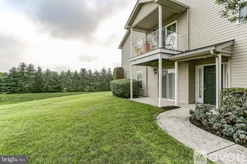 A house with a green door and a balcony overlooking a grassy area.