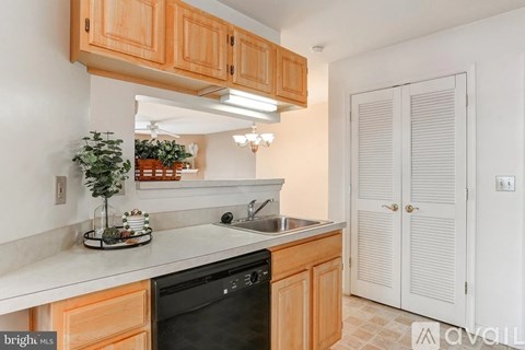 A kitchen with wooden cabinets and a black dishwasher.