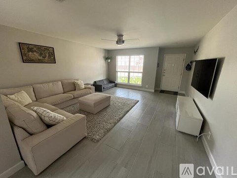 A living room with a beige couch and a rug.