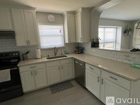 A kitchen with white cabinets and a black stove top oven.