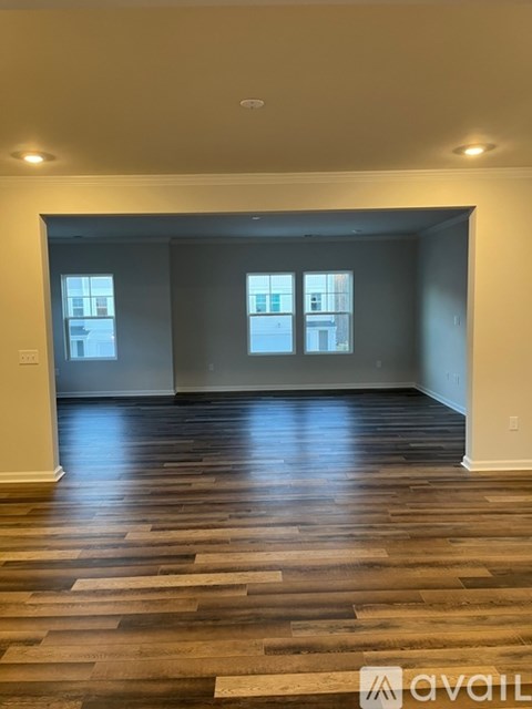 A spacious room with wooden flooring and a large window.