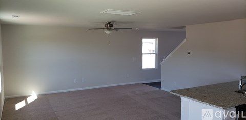 A room with a carpeted floor and a ceiling fan.