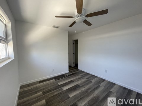 A room with a ceiling fan and wooden flooring.