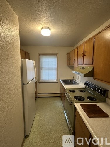A kitchen with a white refrigerator, a stove, and wooden cabinets.
