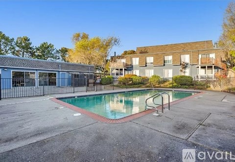 A pool surrounded by a fence with a building in the background.