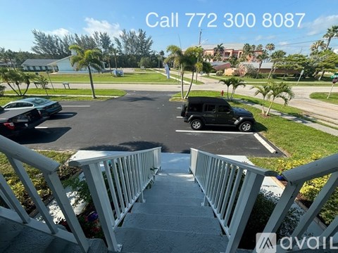 A view of a residential area with a car parked in the driveway and a house in the background.