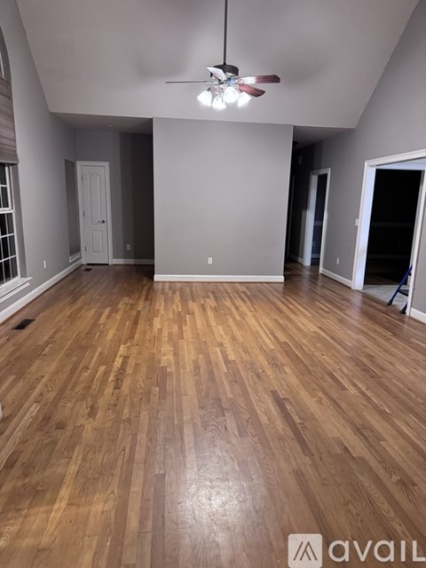 A room with wooden flooring and a ceiling fan.