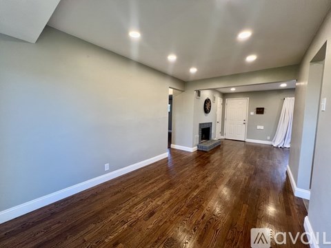 A spacious room with wood flooring and a fireplace.