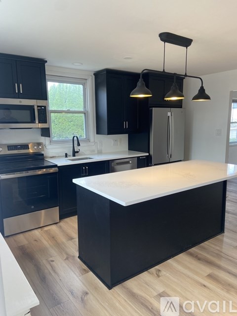 A kitchen with black cabinets and a white island.