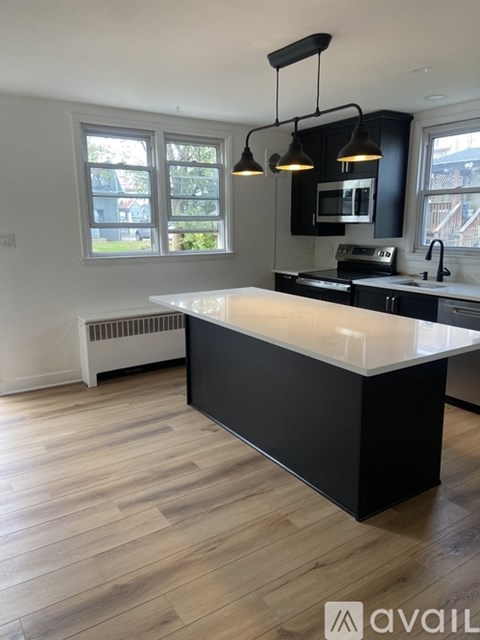 A modern kitchen with a white island and black cabinets.