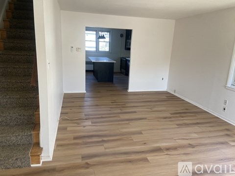 A room with wooden flooring and a staircase on the left side.