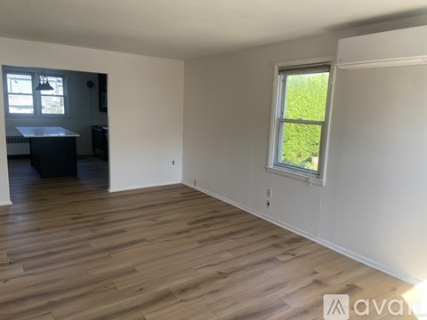 A room with wooden flooring and a window overlooking a green lawn.