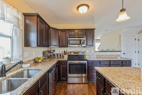 A kitchen with dark brown cabinets and granite countertops.
