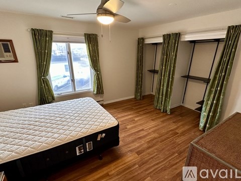 A bedroom with a large bed and a window with green curtains.