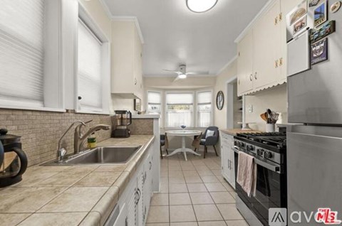 A kitchen with a stove, sink, and cabinets.