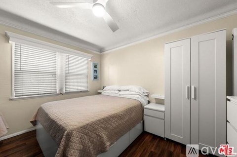 A bedroom with a bed, a window with blinds, and a ceiling fan.