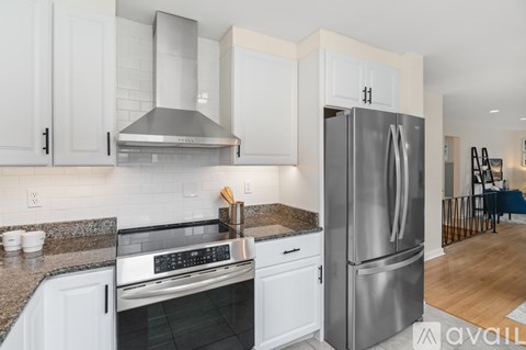 A kitchen with a stainless steel refrigerator and white cabinets.